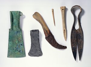 Udvalg af værktøj: L-R: bronzeøkse fra tidlig jernalder med bøjede vinger; senere jernøkse; kniv med knoglehåndtag; knogle nål; ben syl; jernstænger